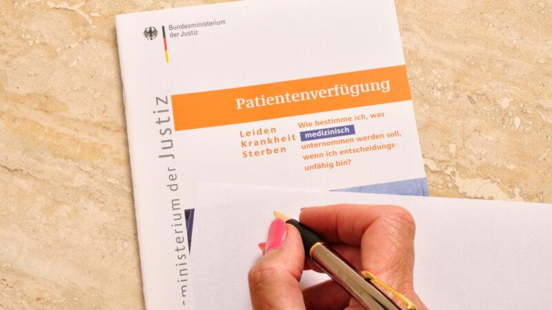 Patientenverfügung mit Hand und Kugelschreiber