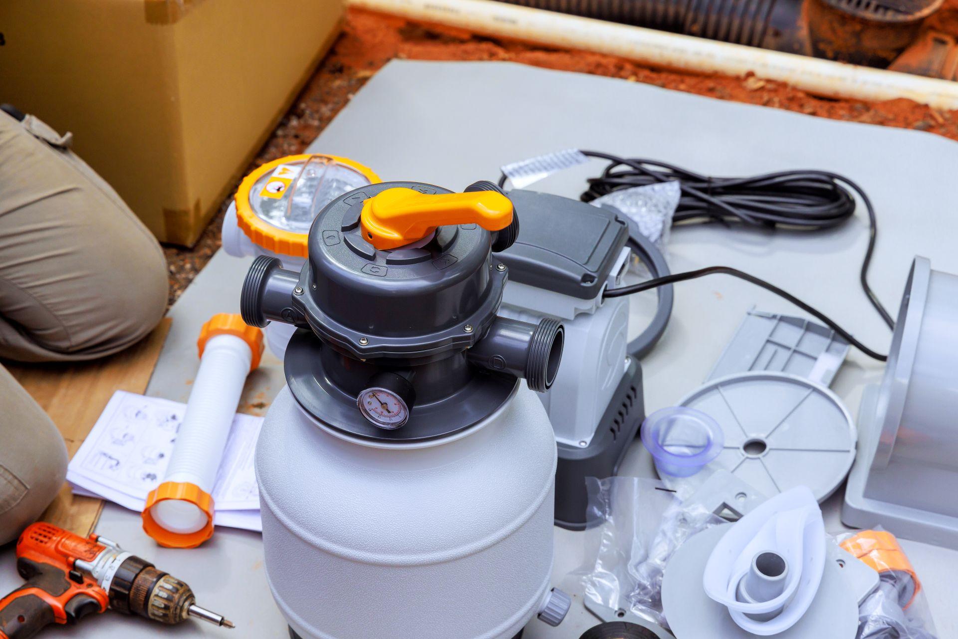 Sandfilteranlage mit Pumpe, Schlauchanschluessen und Werkzeugen bei der Installation aufgestellt
